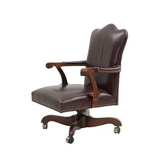 Sillón ejecutivo. Siglo XX. Estilo inglés. En talla de madera. Con respaldo cerrado y asiento de piel color marrón.