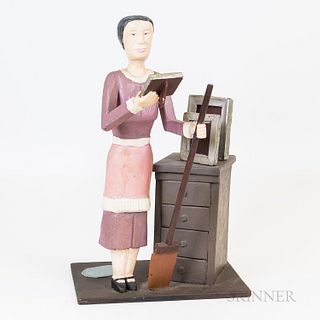 Folk Art Paint-decorated Carving of a Teacher, the figure of a woman dressed in a pink dress holding a book and a broom standing next t