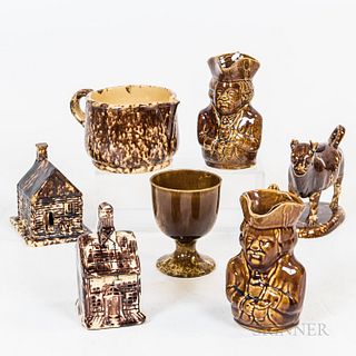 Seven Pieces of Rockingham-glazed and Bennington Pottery, a cabin, signed "W.J. Wein," a bank, two Tobys, a goblet, a cow creamer, and