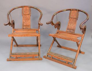 Pair of horseshoe folding/campaign armchairs, China 19th/20th C., possibly Huanghuali wood, with brass fittings, slatted seats and archaic dragon carv