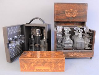 Two sets of tantalus and one enameled box, one antique tantalus and one 20th C. wooden box contains four decanters and eight cups, leather set has thr