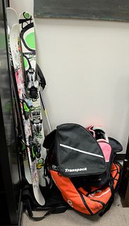 Group of children's snow skis, helmets, goggles, poles and equipment bags.