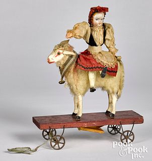 Bisque doll riding a sheep platform pull toy