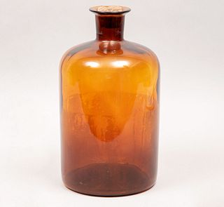 Botellón. México, años 50. En vidrio prensado color ámbar rojizo con tapón de corcho con rastros de parafina.