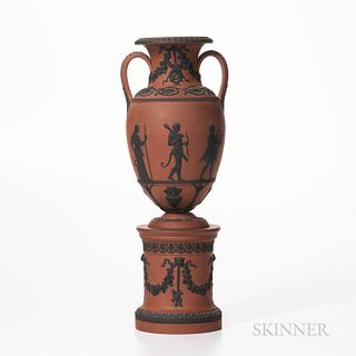 Wedgwood Rosso Antico Vase on Drum Base, England, early 19th century, applied black basalt relief, the vase with trophies and palmettes