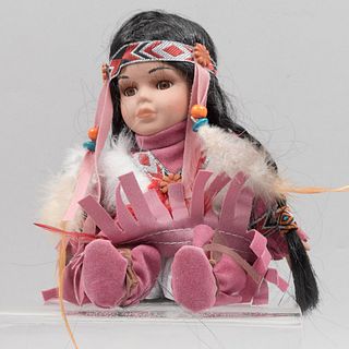 Muñeca nativa americana. sXX. En porcelana, cabello sintético, cuerpo de tela y gamuza camello. Ataviada con vestimenta tradicional.