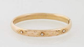 14K Yellow Gold Hinged Bangle Bracelet, c. 1900, the top with three relief medallions with hollowed centers, each mounted with a 10...