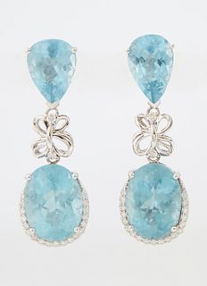 Pair of 14K White Gold Pendant Earrings, each with a pear shaped aquamarine stud suspending a diamond mounted bow bail atop an oval...