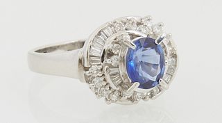 Lady's Platinum Dinner Ring, with a central 1.01 oval sapphire, atop a spiral border mounted with baguette and round diamonds, total...