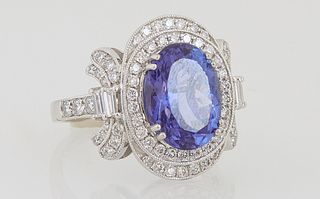 Lady's Platinum Dinner Ring, with an oval 4.62 carat tanzanite atop a border of round diamonds, the top and bottom with semi-circular