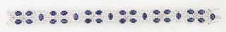 14K White Gold Link Bracelet, each of the 12 links with two oval horizontal blue sapphires on swirled diamond borders, six links joi...