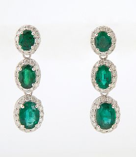 Pair of 18K White Gold Pendant Earrings,with an oval emerald mounted stud atop a border of diamonds, suspending two like oval gradua...