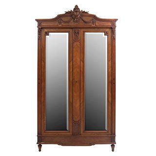 Armario. Francia. Siglo XX. En talla de madera de nogal. 2 puertas abatibles con espejos de luna irregular y soportes tipo carrete.
