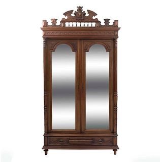 Armario. Francia. Siglo XX. Estilo Enrique II. En talla de madera de nogal. Con 2 puertas abatibles, espejos de luna irregular.