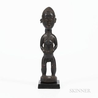 Baule Standing Female Figure, Ivory Coast, standing on a rounded base, bent legs supporting an elongated torso with hands to the abdome