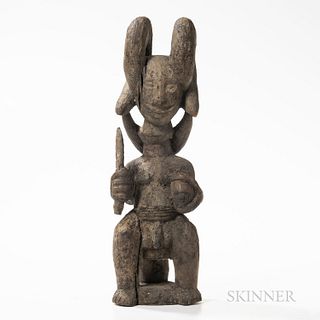 Igbo Warrior Figure, Ikenga, Nigeria, seated on a stool, holding sword in right hand, and human head in left, with swollen, elongated n
