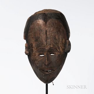 Ibo Maiden Spirit Mask, Nigeria, helmet form, the delicately carved face with open, pursed lips exposing teeth, beneath a narrow, point