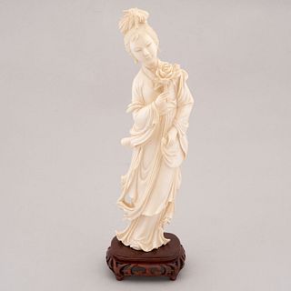 Guan Yi. China. Siglo XX. En talla de marfil. Con base de madera tallada. 25 x 7 x 4 cm