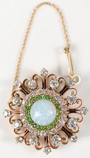 14 Karat Gold Brooch/Pendant
with center fire opal, encircled by green garnets, surrounded by rows of diamonds
diameter approximately 4 carats total w