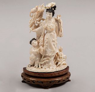Quan Yin con niña. China, siglo XX. Talla en marfil con detalles en tinta negra y base de madera. 18 cm de altura
