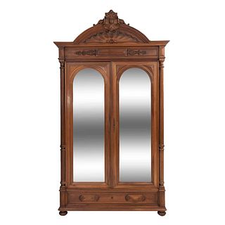 Armario. Francia. Siglo XX. Estilo Enrique II. En talla de madera de nogal. Con 2 puertas abatibles, con espejo de luna irregular.
