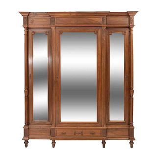 Armario. Francia. Siglo XX. Estilo Enrique II. En talla de madera de nogal. Con cajón, 3 puertas abatibles con espejos.