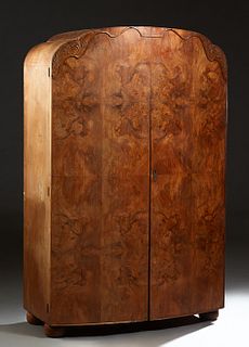 English Art Deco Carved Walnut Double Door Armoire, c. 1940, the arched serpentine top over two highly figured doors, on large bun feet, the interior 