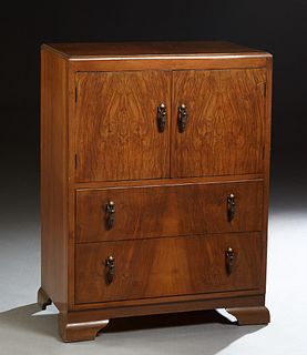 English Art Deco Carved Walnut Chest, c. 1940, the stepped rectangular top over double cupboard doors enclosing a shelved interior, above two drawers,