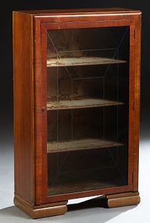 English Art Deco Carved Mahogany Bookcase, c. 1940, the rectangular top over a single glazed door with interior geometric incised decoration, on stepp