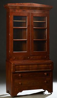 American Carved Walnut Secretary Bookcase, 19th c., the peaked sloping crown over double glazed mullioned doors above two frieze drawers, on a base wi