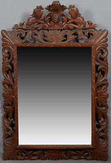 French Provincial Carved Mahogany Henri II Style Overmantle Cushion Mirror, late 19th c., with a pierced lion coat of arms rest, over a pierced leaf f