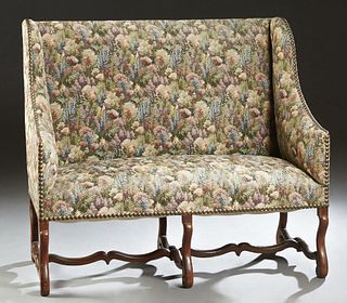 French Louis XIII Style Carved Walnut Settee, 20th c., the high back flanked by curved winged arms, to a cushioned seat, on six scrolled cabriole legs