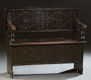 French Provincial Henri II Style Ebonized Oak Bench, 19th c., the canted floral relief carved back over two relief leaf carved scrolled arms, above a 