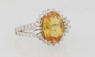 Lady's Platinum Dinner Ring, with an oval 4.43 carat yellow sapphire atop a border of round and baguette diamonds, the split shoulders of the band als