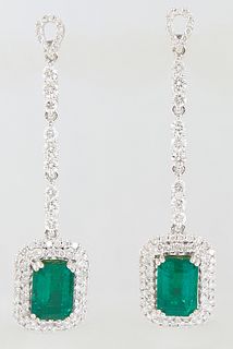 Pair of 18K White Gold Pendant Earrings, the pear shaped diamond mounted stud over a 9 round diamond chain to a pendant 3.28 carat emerald atop a conc