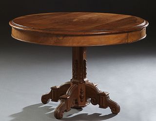 French Carved Walnut Center Table, 19th c., the rounded edge circular top over a wide skirt with two drawers, on a tapered applied carving support, to