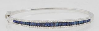 14K White Gold Hinged Bangle Bracelet, with a central row of graduated baguette blue sapphires, within borders of small round diamonds, total sapphire