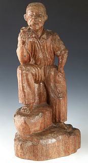 American Folk Art Carved Wooden Figure, 19th c., of a seated Afro-American man smoking a pipe, carved from a single log, H.- 22 in., W.- 10 1/2 in., D