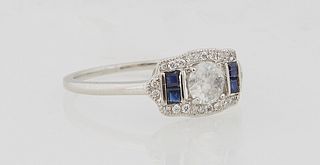 Lady's Platinum Dinner Ring, with a central. 35 carat round diamond, flanked by baguette sapphires, with a curved border of tiny round diamonds, diamo