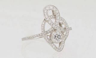 Lady's Platinum Dinner Ring, of pierced swirled design, with a center .3 carat round diamonds flanked by borders of tiny round white diamonds, the sho