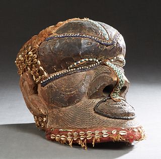 African Carved Wood Helmet Mask, 20th c., with cloth, beadwork, and cowrie shell decoration, H.- 12 in., W.- 10 in., D.- 16 in. Provenance: from the E