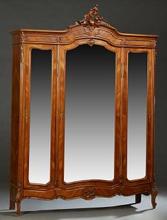 French Louis XV Style Carved Walnut Armoire, early 20th c., the arched crown with a pierced C-scroll and floral carved crest over a central arched wid