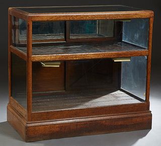Carved Oak Two Tier Tobacco Display Case, early 20th c., with a glass top and sides, verso with double sliding doors top and bottom, on a plinth base,