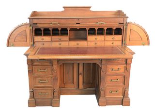 Two Piece Lot to include
Walnut Cylinder Roll Top Desk with hinged wings, gallery, recessed panels;
along with a Victorian caned, swivel, office chair