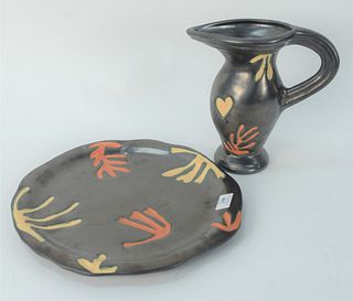 Two Julie Sanders Cyclamen Pottery pieces, to include one pitcher, and one charger, each marked to the underside, pitcher 10 3/4 inches, charger diame