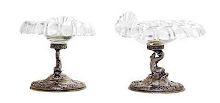 A Pair of German Silver and Glass Compotes, First Half 20th Century, having etched glass shell form bowls raised on dolphin form