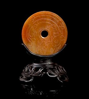 A Chinese Red Jadeite Bi Disk Mounted in Carved Wood Stand LATE 19TH/EARLY 20TH CENTURY