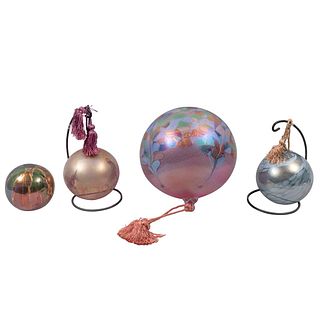Juego de 4 esferas. Siglo XX. Elaboradas en vidrio soplado. Acabado iridiscente. Difrentes colores y tamaños. Con 3 bases de metal.