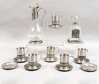 Lote de 24 piezas. SXX Elaboradas en pewter, estaño y vidrio. Consta de: jarra, licorera, 12 platos base y 6 tazas con 5 platos base.