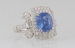 Lady's Platinum Dinner Ring, with a cushion cut 3.39 ct. blue sapphire atop a double concentric border of round diamonds, flanked by diamond mounted l